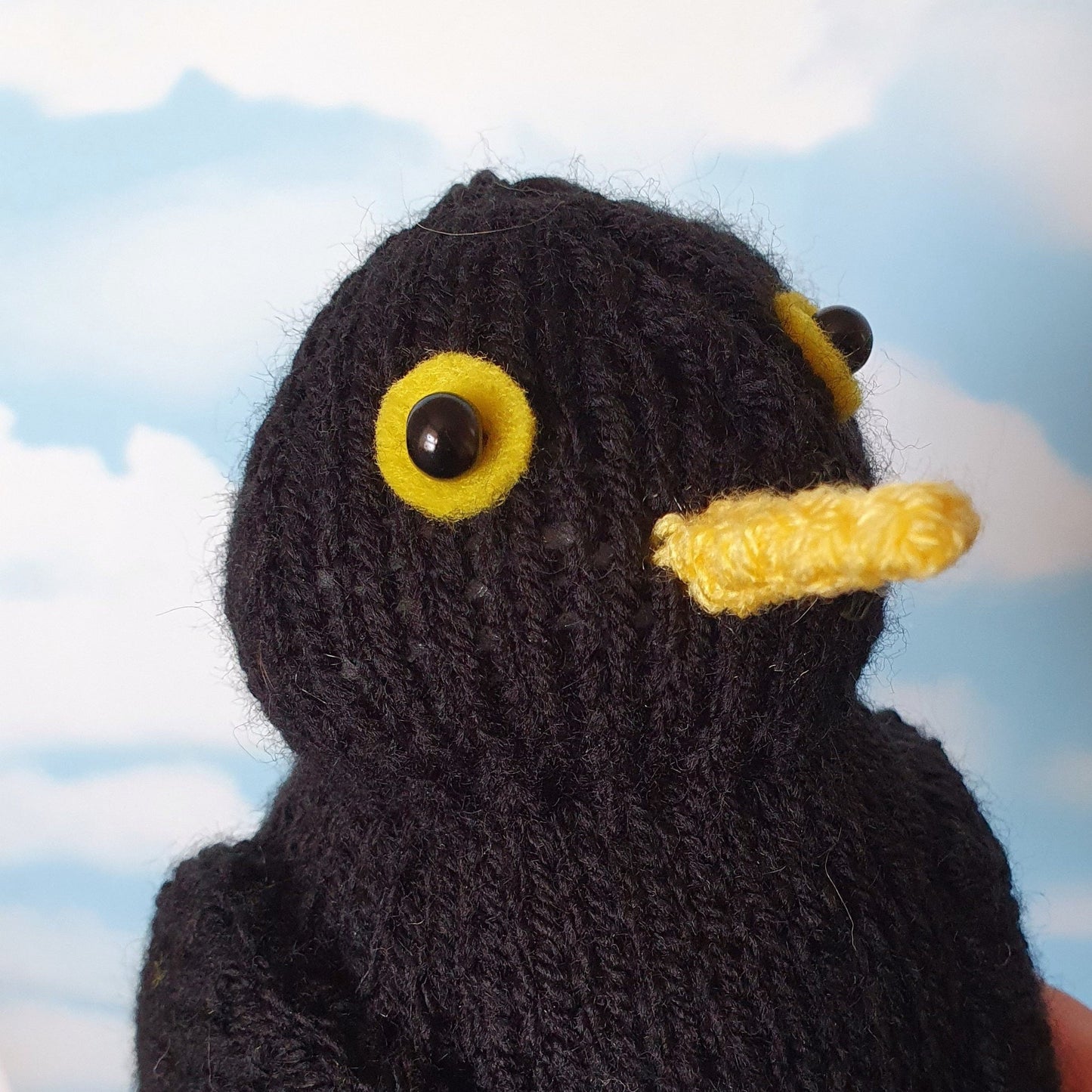 a knitted blackbird against a blue sky background