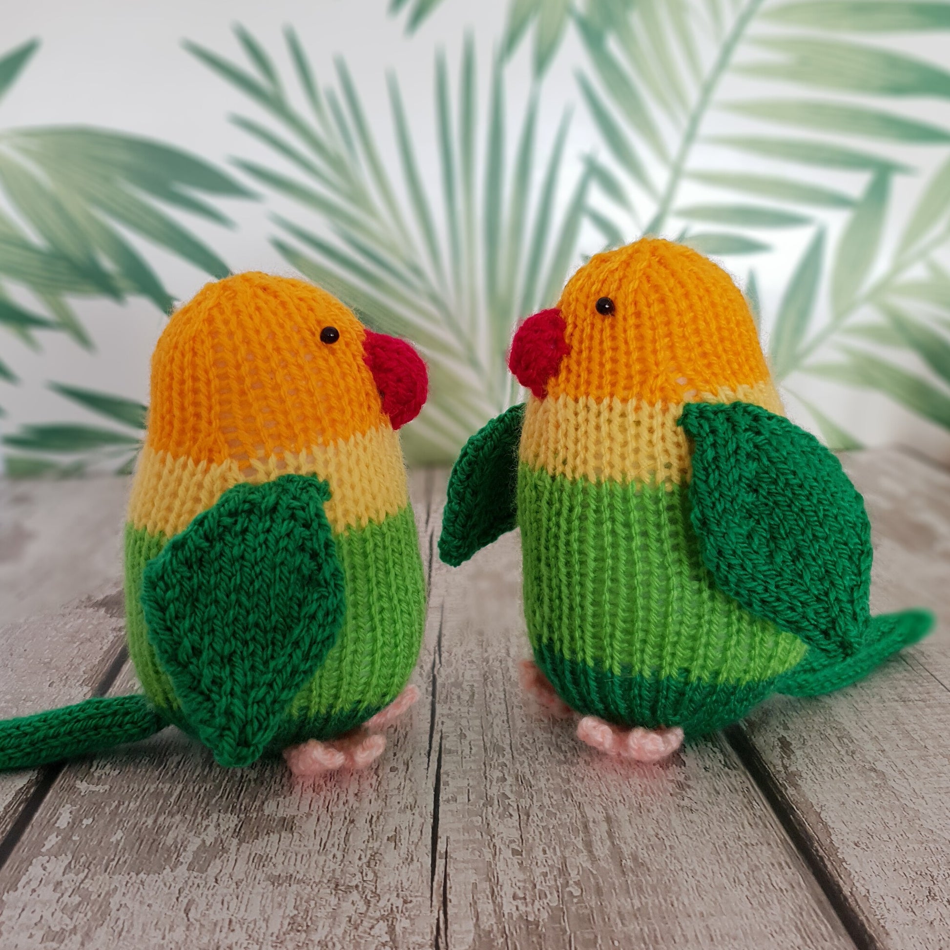 two knitted lovebirds designed by Nicky Stewart, facing each other with green ferns in the background