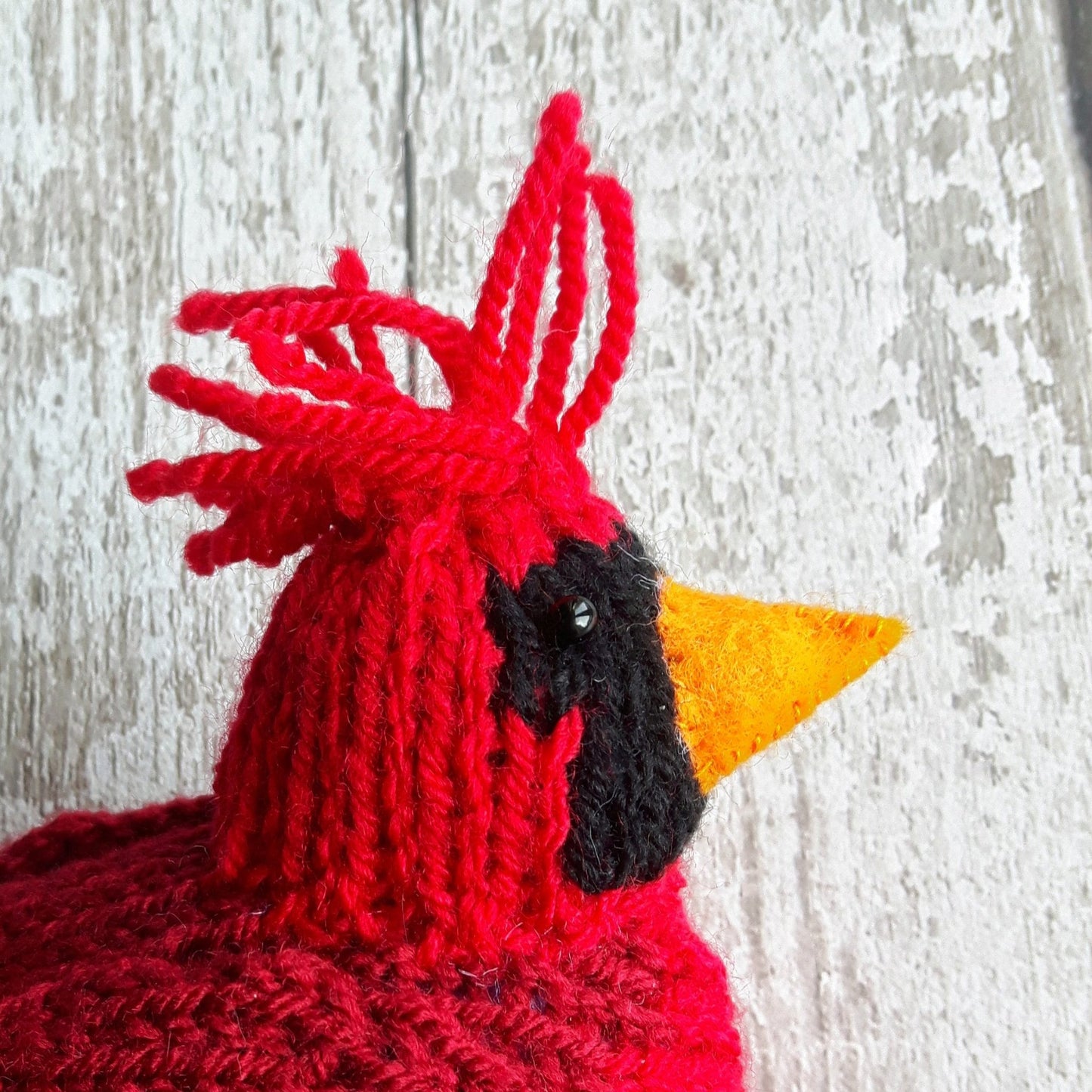 a head of a red northern cardinal bird with an orange felt beak