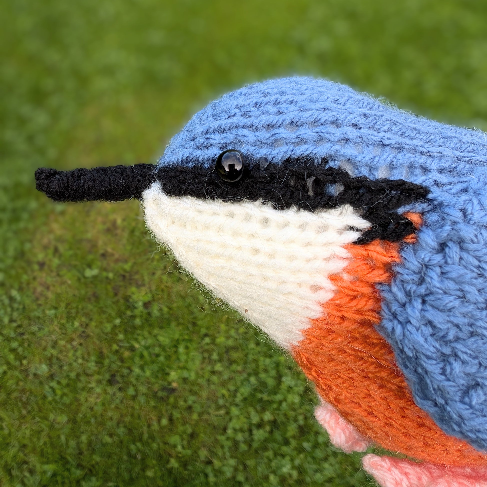 a knitted nuthatch bird with grass in the background